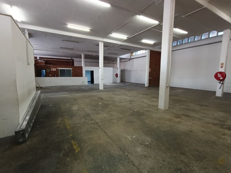 Spacious industrial warehouse unit featuring open-plan floor space, exposed structural columns, and functional overhead lighting, suitable for various commercial or storage applications.