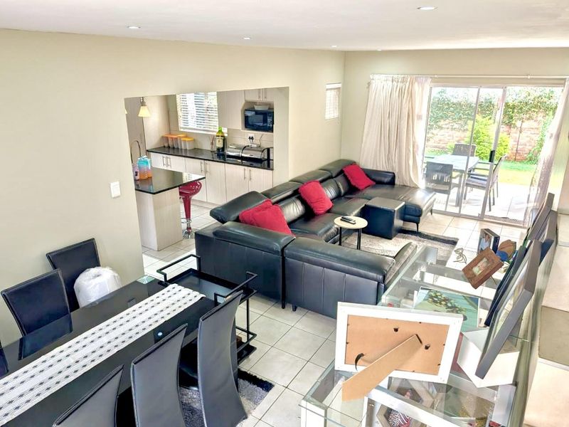 Open-plan living and dining area featuring tiled floors, recessed lighting, and a functional kitchen with granite countertops, flowing out to a patio.