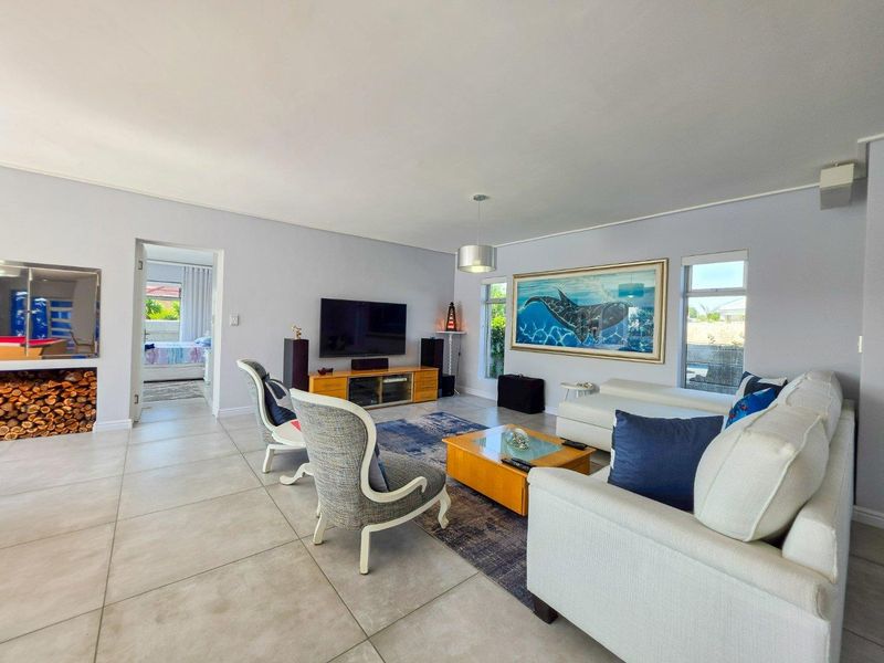Spacious living room featuring large windows, neutral tiled flooring, and a clean, well-maintained interior layout.