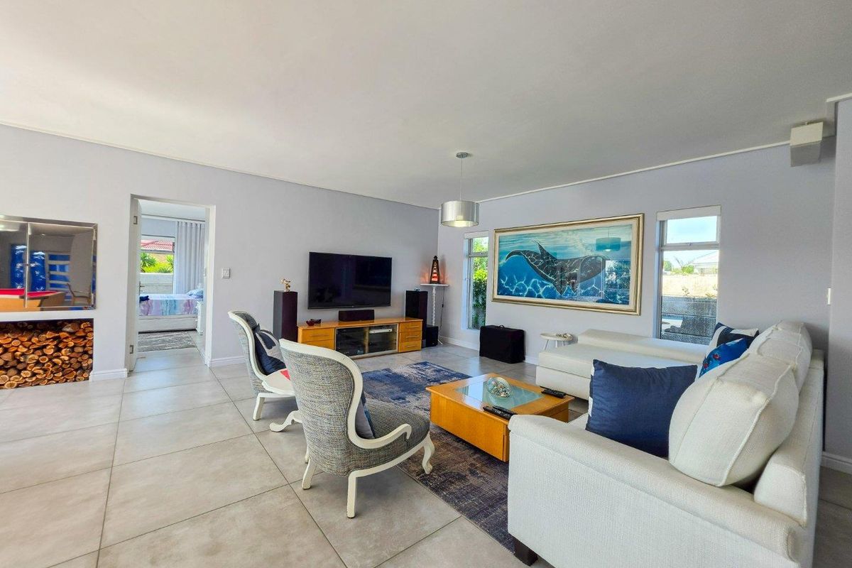 Spacious living room featuring large windows, neutral tiled flooring, and a clean, well-maintained interior layout.