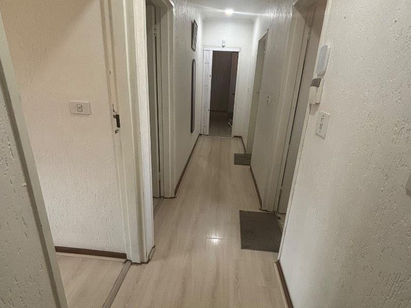 A functional hallway featuring light-toned laminate flooring and textured walls, providing access to multiple rooms within the townhouse.