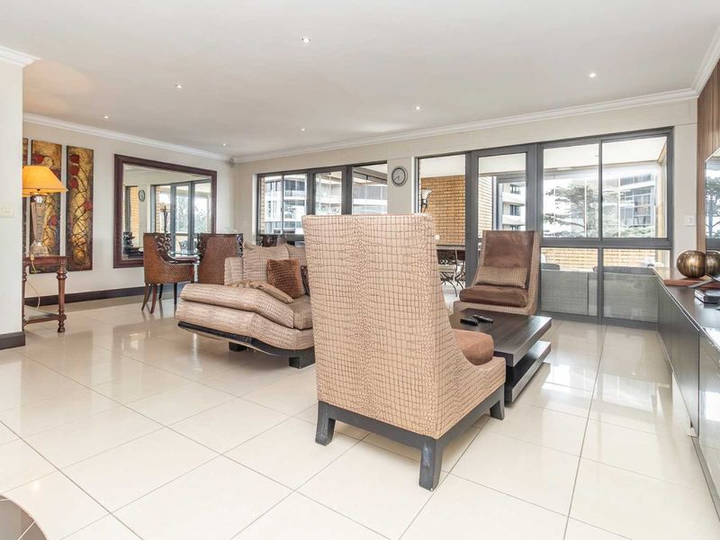 Spacious living room featuring polished tiled flooring, recessed downlighting, and large sliding glass doors providing access to the balcony.