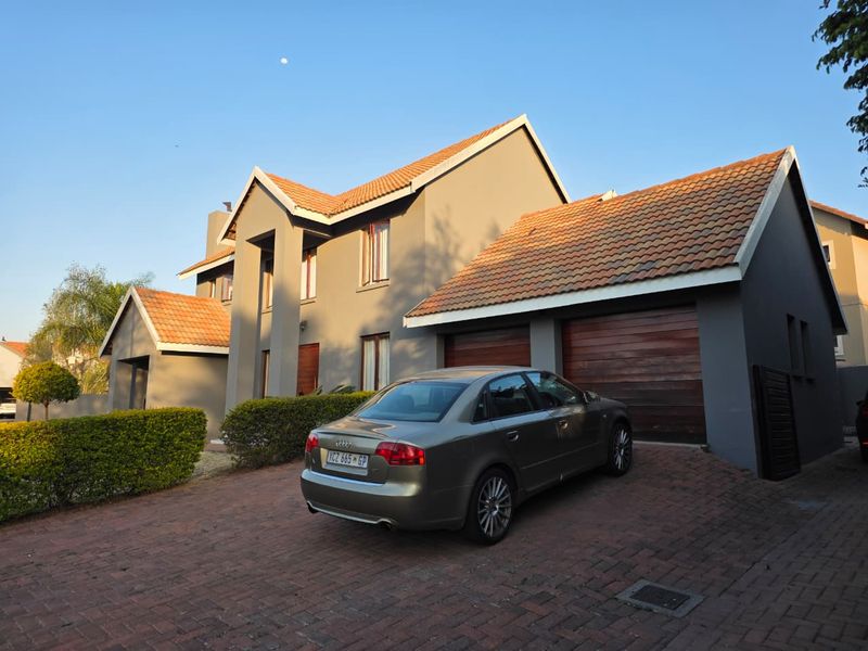 Front elevation of a double-storey house featuring a paved driveway, double garage with timber doors, and a tiled roof.
