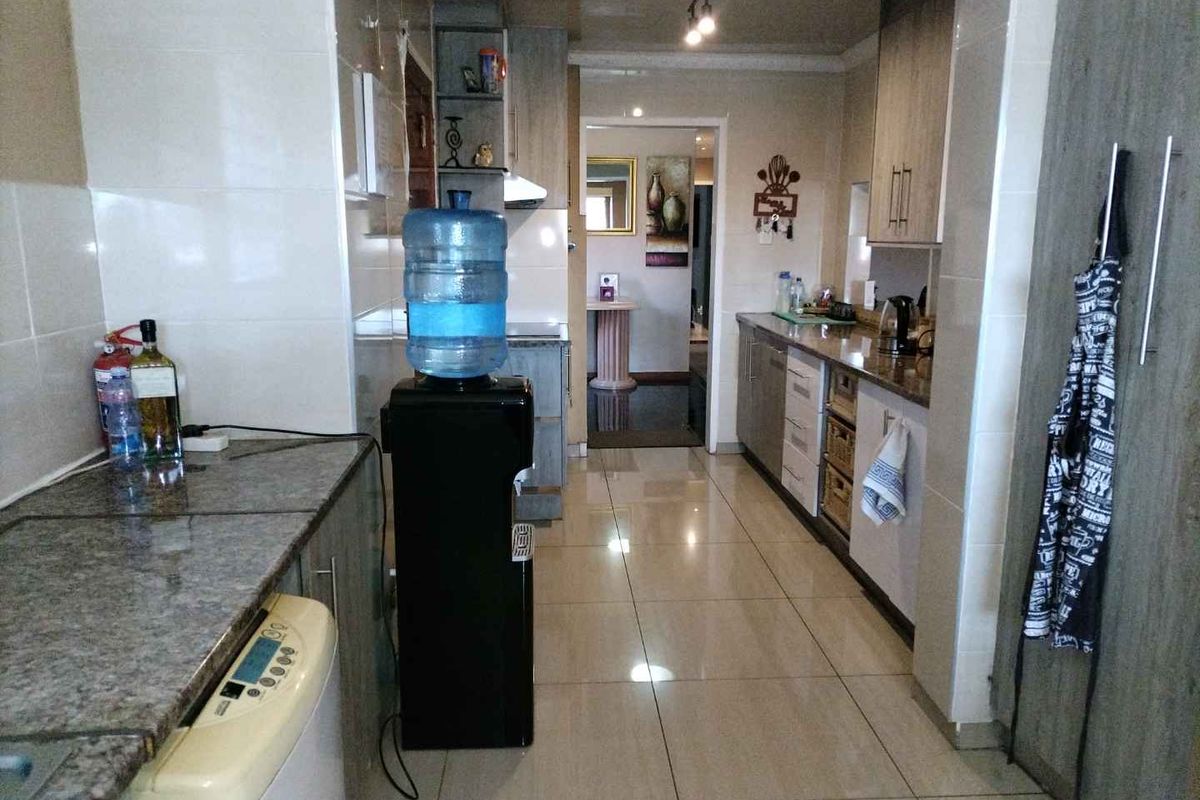 A functional kitchen featuring granite countertops, tiled flooring, and ample built-in cabinetry with a clean, modern aesthetic.