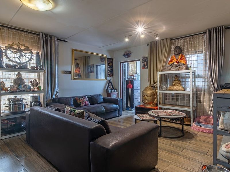 A living room featuring wood-look tile flooring and dual ceiling lighting fixtures, providing a functional space for relaxation.