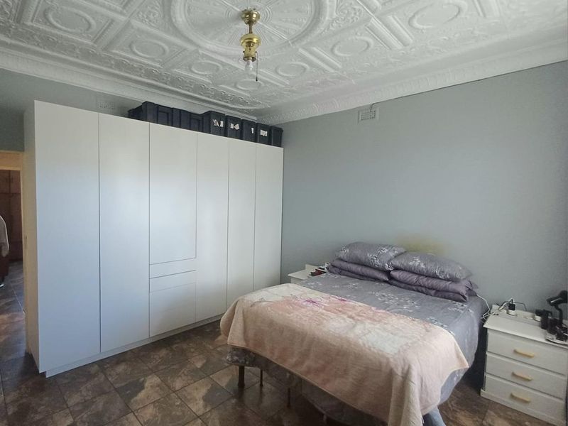 Bedroom featuring a distinctive ornate pressed metal ceiling, tiled flooring, and a large built-in wardrobe providing ample storage space.