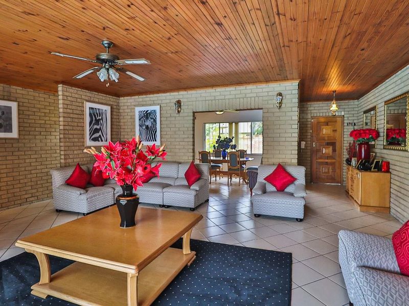 Spacious open-plan living and dining area featuring exposed brick walls, a warm timber ceiling, and neutral ceramic floor tiles.
