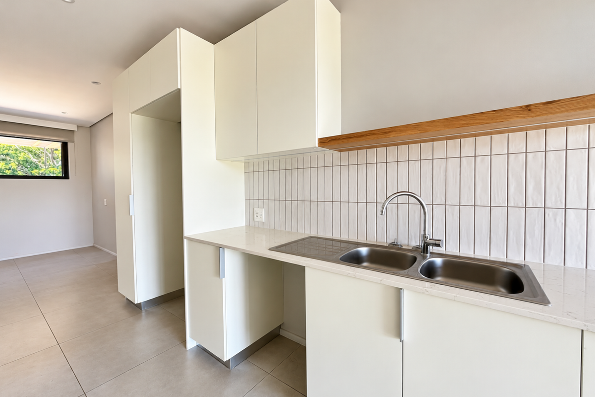 Modern kitchen featuring clean white cabinetry, stone countertops, a stainless steel double sink, and a stylish tiled splashback with a floating timber shelf.