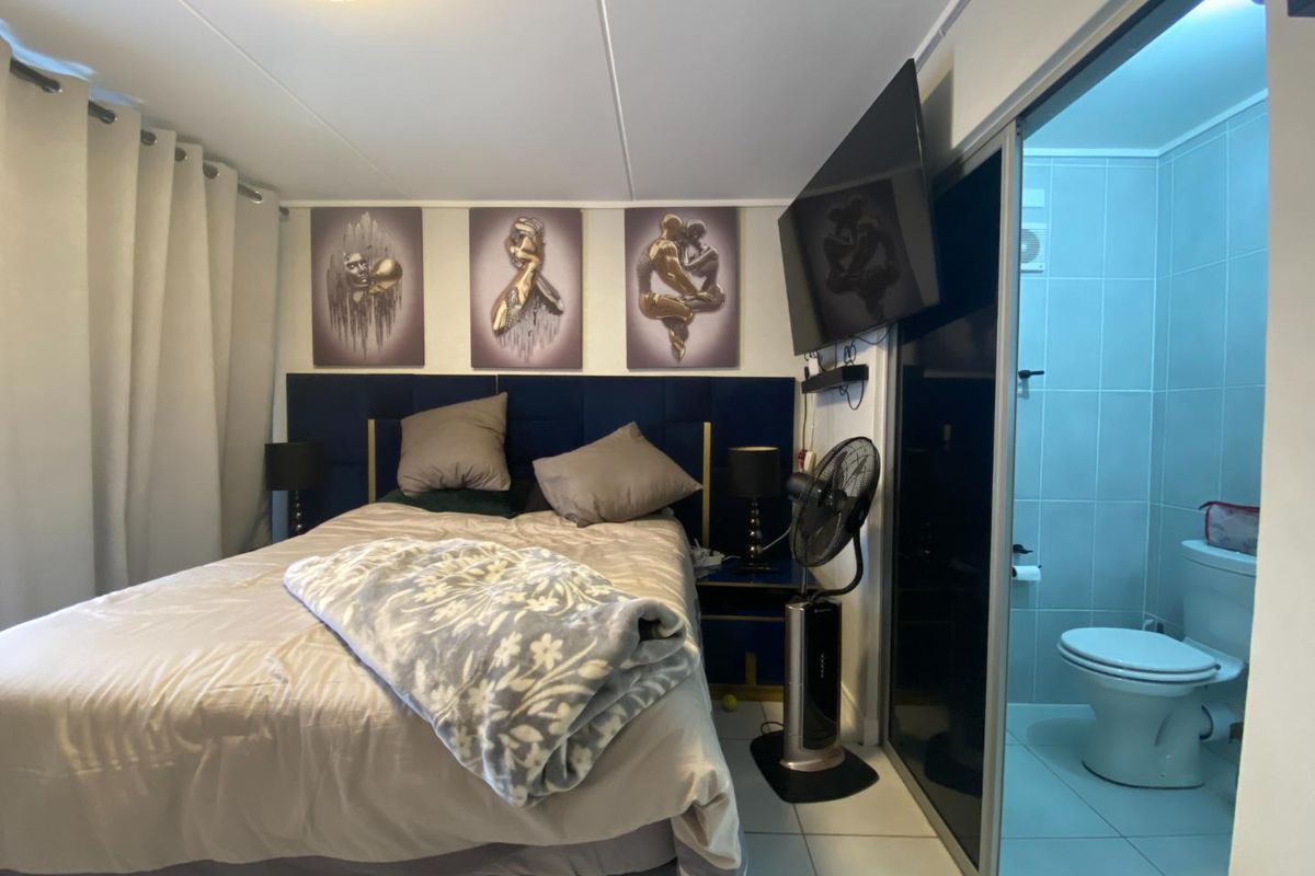 A bedroom featuring an en-suite bathroom with tiled flooring and a modern layout, providing a functional living space.
