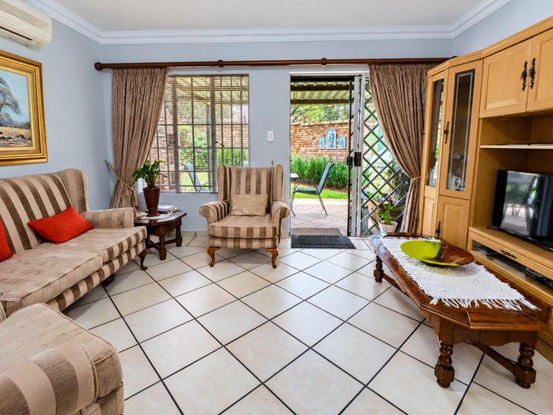 A comfortable living room featuring ceramic floor tiles, crown molding, and direct access to an outdoor patio area through a sliding glass door.