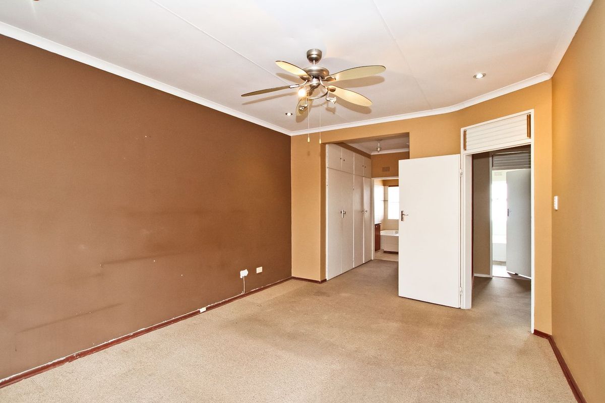 An empty bedroom featuring built-in cupboards, a ceiling fan, and carpeted flooring, offering a blank canvas for personalization.