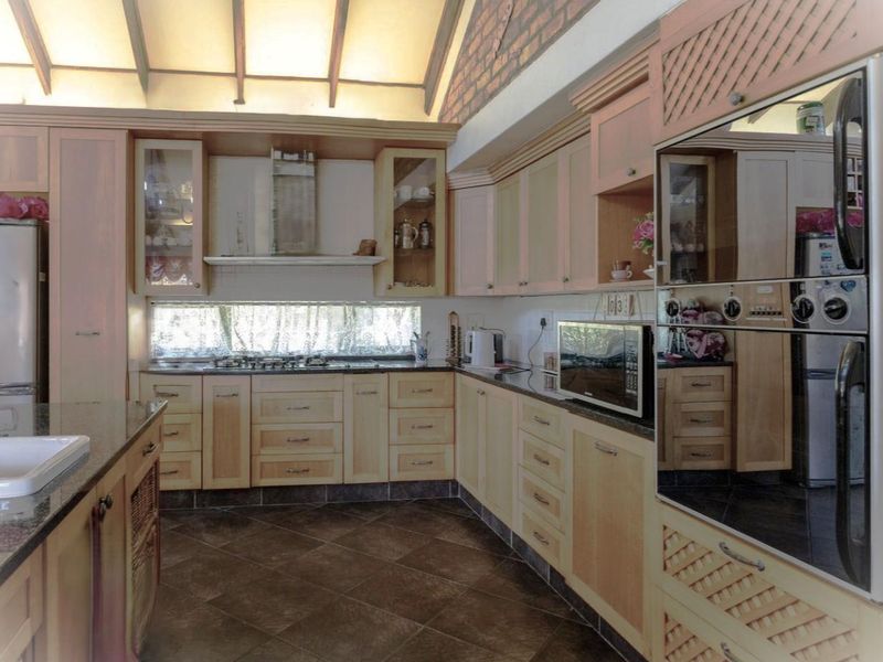 Spacious kitchen featuring light wood cabinetry, granite countertops, built-in appliances, and a distinctive vaulted ceiling with exposed brickwork.