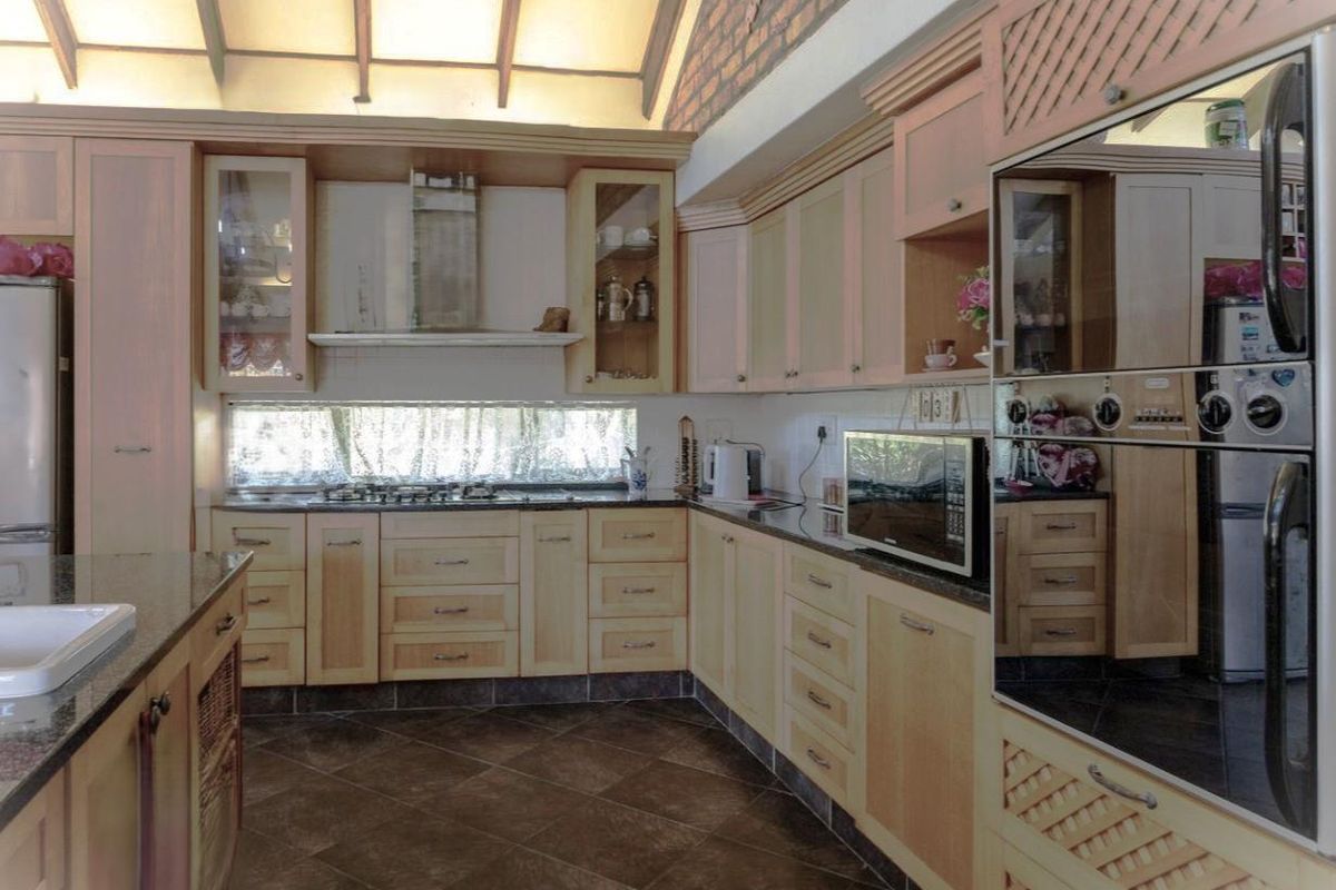 Spacious kitchen featuring light wood cabinetry, granite countertops, built-in appliances, and a distinctive vaulted ceiling with exposed brickwork.