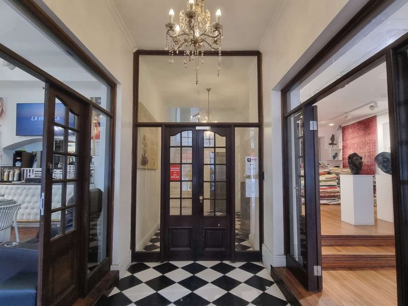 A grand entrance foyer featuring classic black and white checkerboard floor tiles, elegant timber-framed glass doors, and a decorative chandelier.