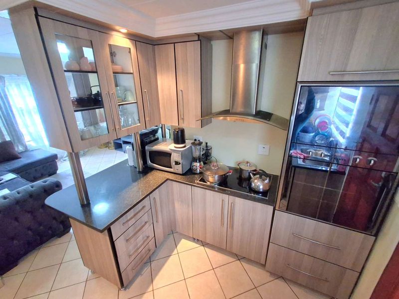 Compact kitchen featuring modern laminate cabinetry, granite countertops, stainless steel appliances, and tiled flooring, seamlessly integrated into an open-plan living space.