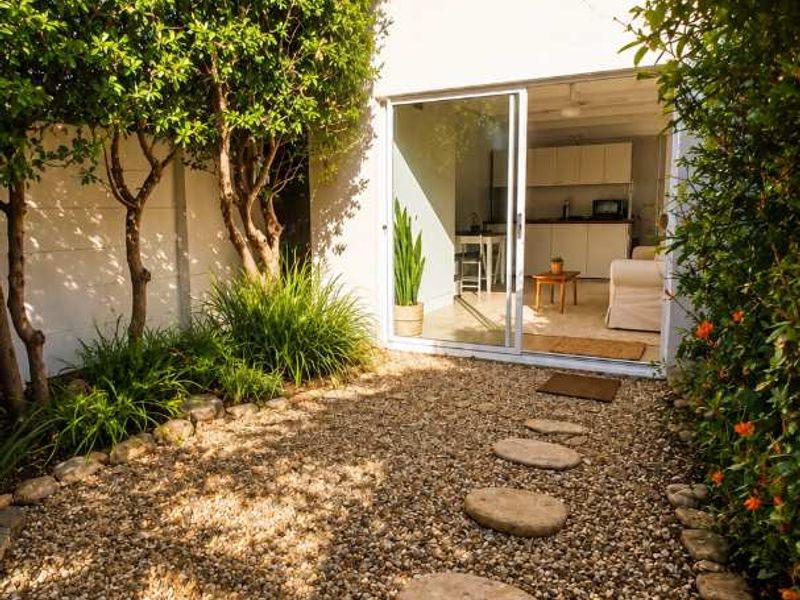 A private rear courtyard featuring a gravel garden with stone stepping stones and a sliding glass door providing access to the interior living space.