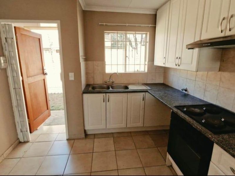 A functional kitchen featuring white cabinetry, dark countertops, a built-in oven and hob, and direct access to the exterior.