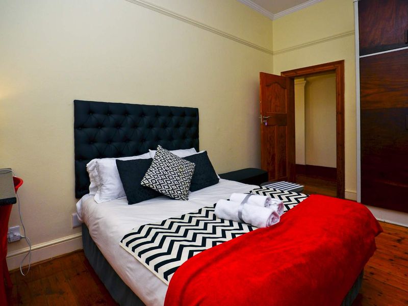 A bedroom featuring timber flooring, built-in wardrobe storage, and classic architectural detailing including skirting boards and door architraves.
