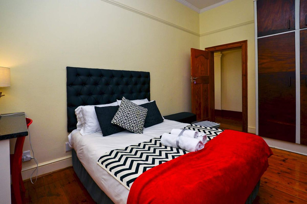 A bedroom featuring timber flooring, built-in wardrobe storage, and classic architectural detailing including skirting boards and door architraves.