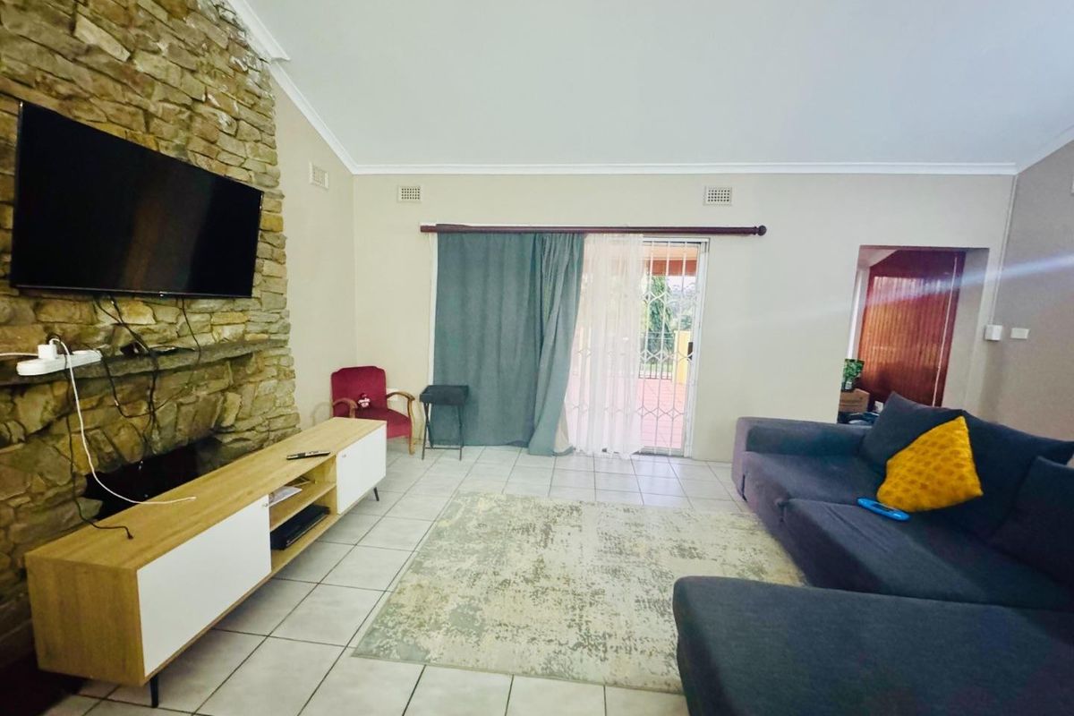 Spacious living room featuring a prominent stone fireplace, tiled flooring, and a sliding glass door providing access to the outdoor area.