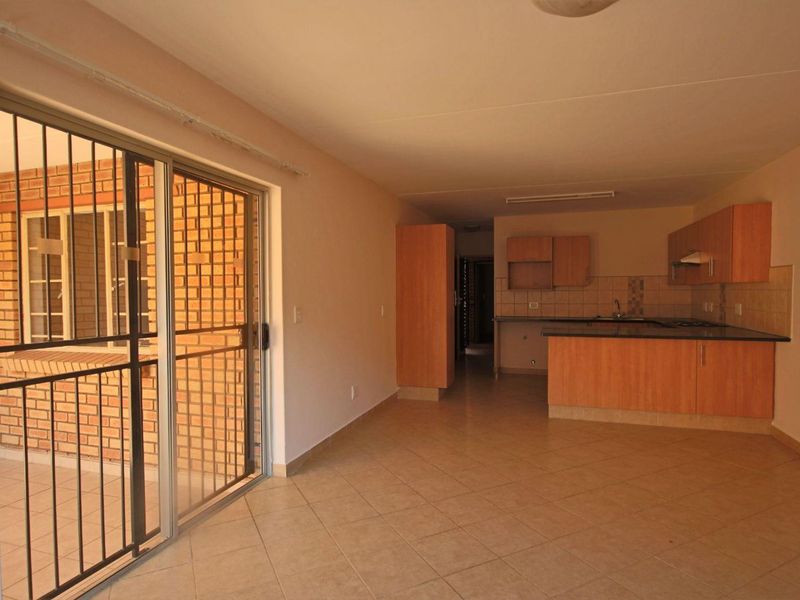 Open-plan living area featuring tiled floors, a functional kitchen with granite countertops, and a sliding door leading to an outdoor patio space.