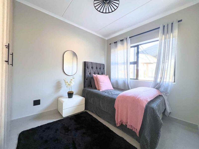 A well-maintained bedroom featuring neutral wall tones, a window with natural light, and a modern ceiling light fixture.