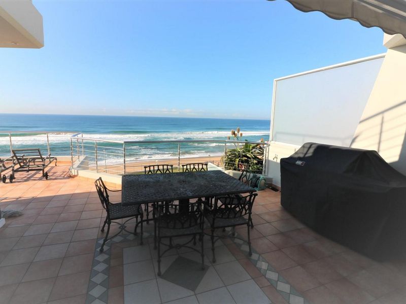 Spacious balcony featuring tiled flooring, a stainless steel balustrade, and a retractable awning, offering expansive ocean views.