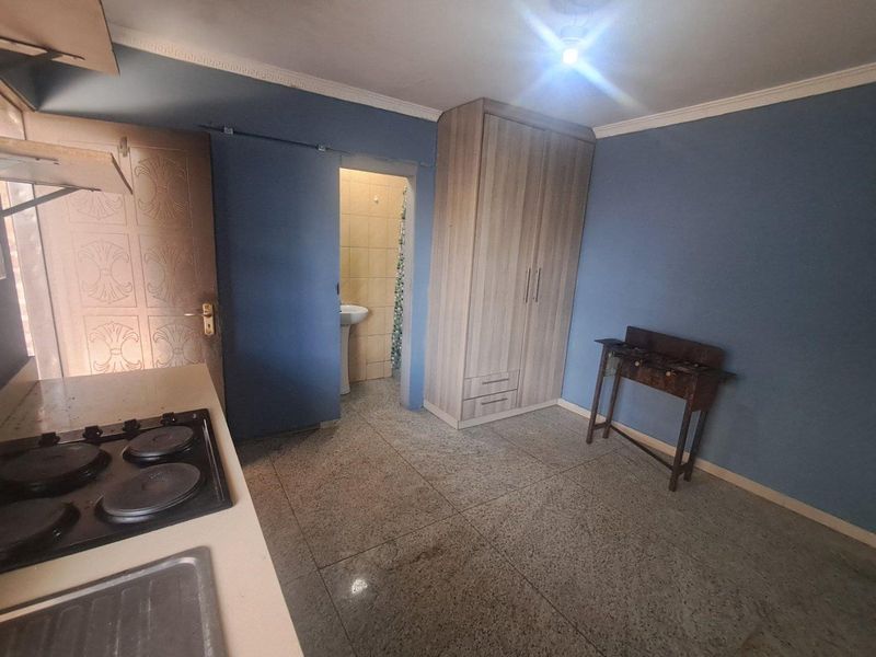 Open plan living area featuring a built-in wardrobe, kitchenette with hob and sink, and direct access to an en-suite bathroom.