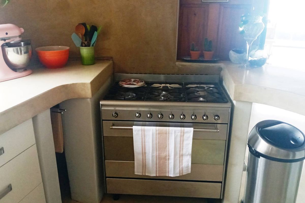 A kitchen area featuring a built-in stainless steel gas stove and oven set within custom concrete-style countertops and cabinetry.