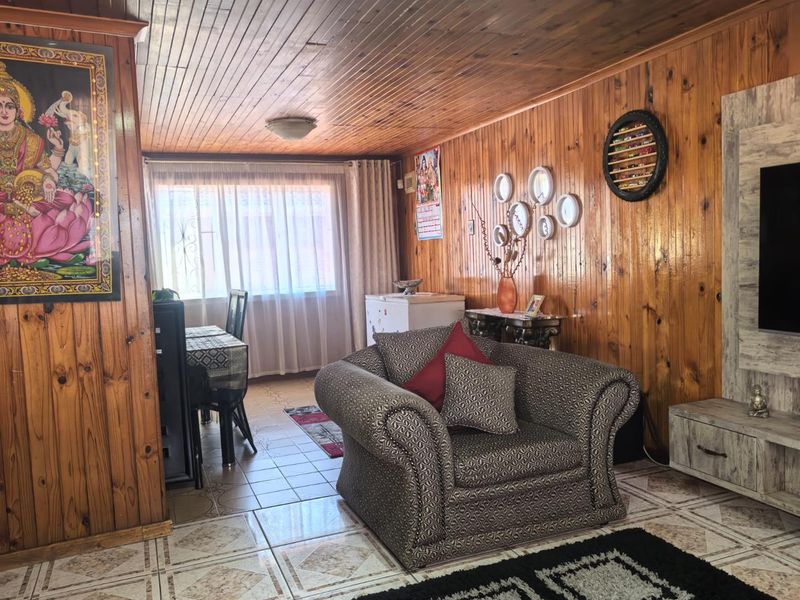 Living room featuring extensive timber wall and ceiling paneling with tiled flooring and natural light from the window.