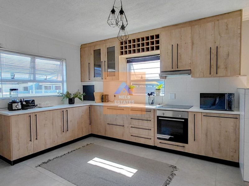Modern kitchen featuring light wood-finish cabinetry, integrated appliances, and ample counter space, creating a functional and contemporary culinary environment.