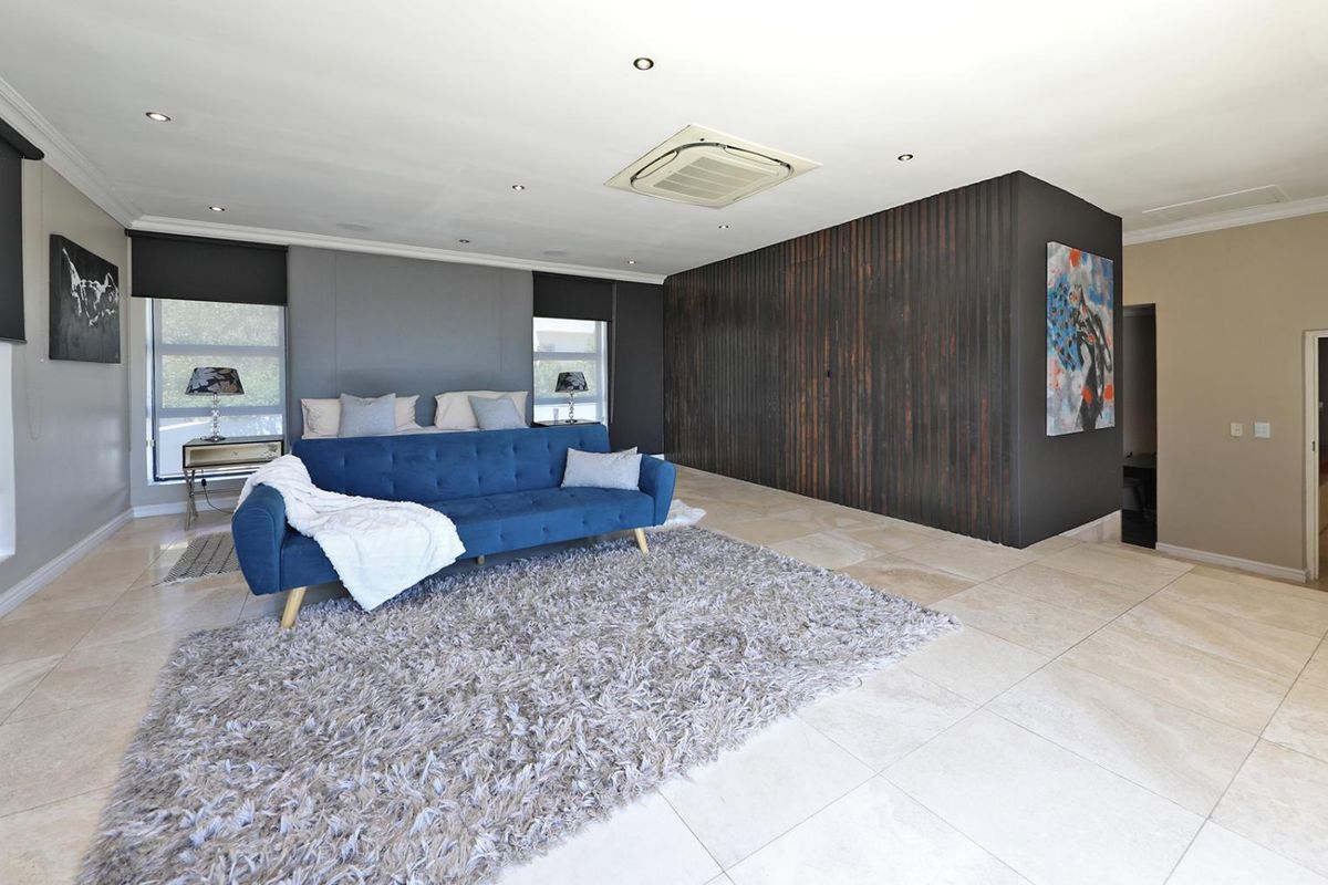 Spacious bedroom featuring large format floor tiles, recessed ceiling lighting, and a central air conditioning unit, offering a modern and comfortable living space.