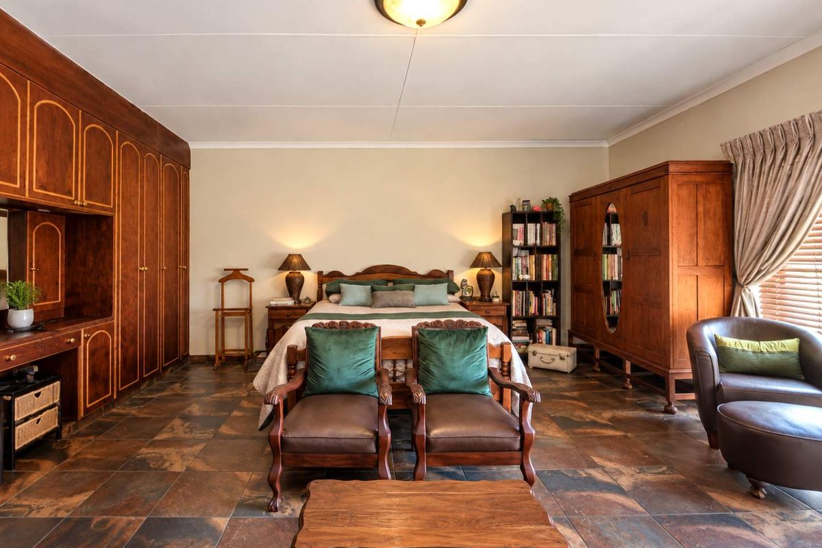 Spacious bedroom featuring extensive built-in wooden cabinetry, tiled flooring, and a central ceiling light fixture.