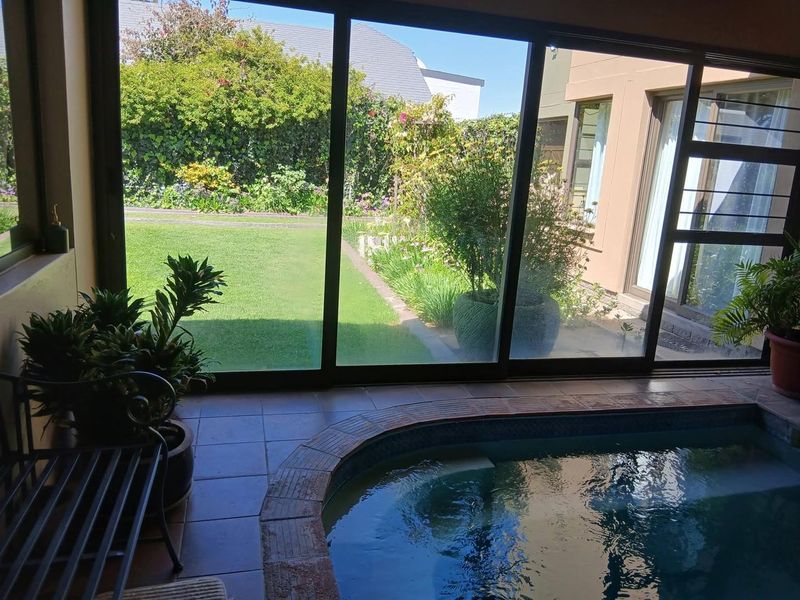 Indoor swimming pool area featuring large sliding glass doors that open onto a private garden, providing a seamless transition between indoor and outdoor spaces.