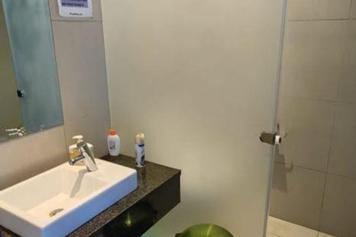 A modern bathroom featuring a sleek vanity with a countertop basin, tiled flooring, and a frosted glass partition door.