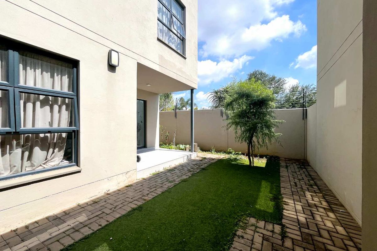 A private rear garden featuring a paved patio area, artificial lawn, and perimeter boundary walls, providing a low-maintenance outdoor space.