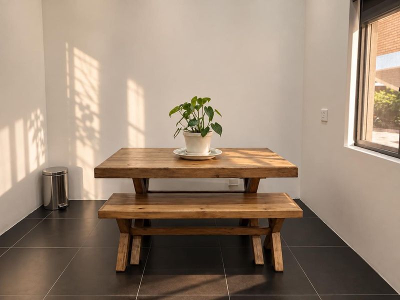 A bright dining area featuring dark tiled flooring and natural light streaming through a side window.