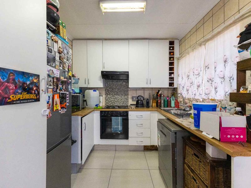 Functional kitchen featuring white cabinetry, built-in oven, hob, extractor fan, and tiled splashback with ample counter space.