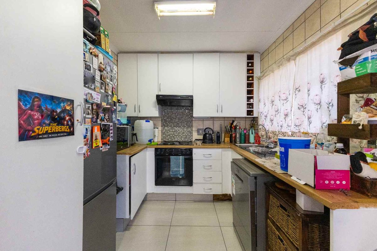 Functional kitchen featuring white cabinetry, built-in oven, hob, extractor fan, and tiled splashback with ample counter space.