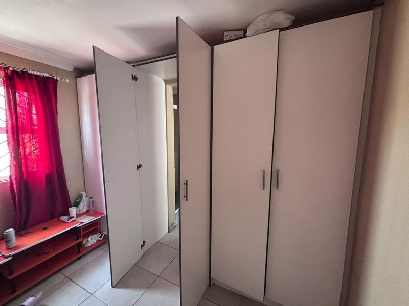 Bedroom featuring built-in cupboards with white finish and tiled flooring.