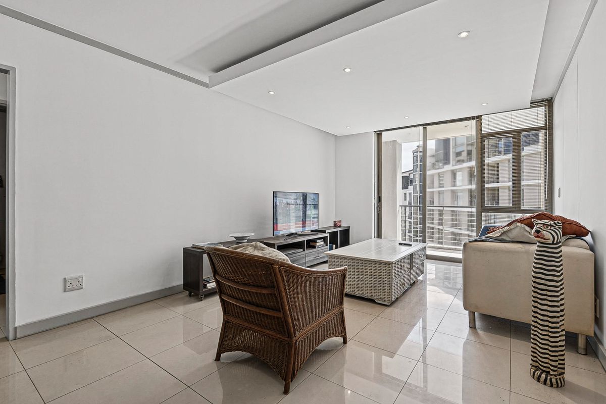 A bright living room featuring tiled flooring, recessed ceiling lighting, and large sliding glass doors leading to a balcony.