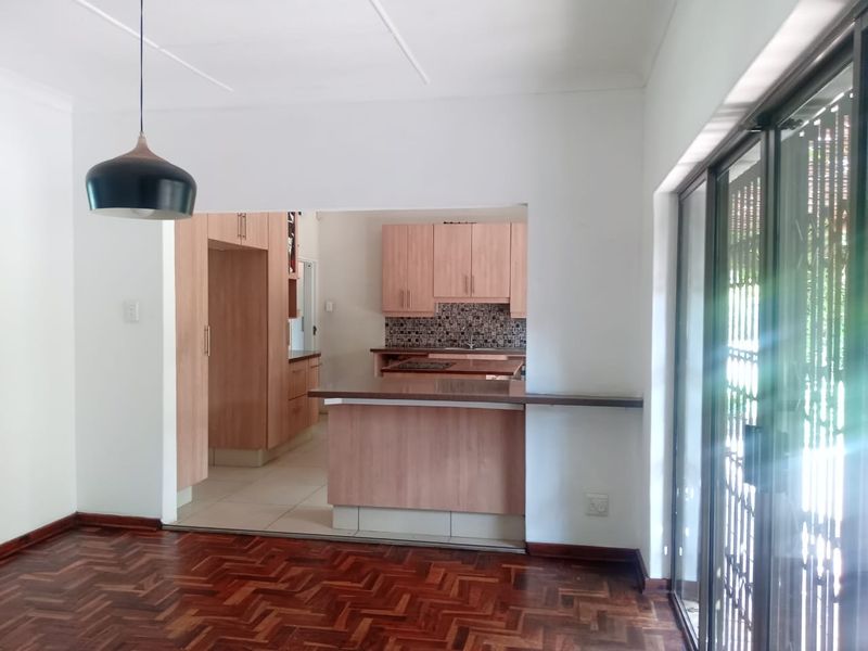 Open plan living area featuring parquet flooring, a functional kitchen with built-in cabinetry, and direct access to the outdoors via sliding glass doors.
