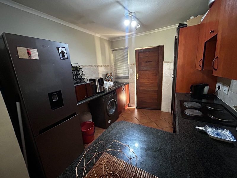 Functional kitchen featuring granite countertops, built-in cabinetry, electric hob, and direct access to an exterior door.
