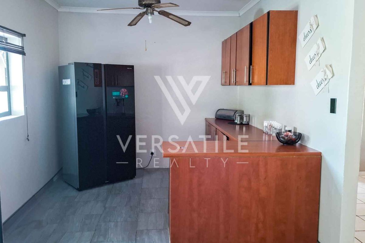 A functional kitchen area featuring wooden cabinetry, a breakfast counter, and tiled flooring, providing a practical space for meal preparation.