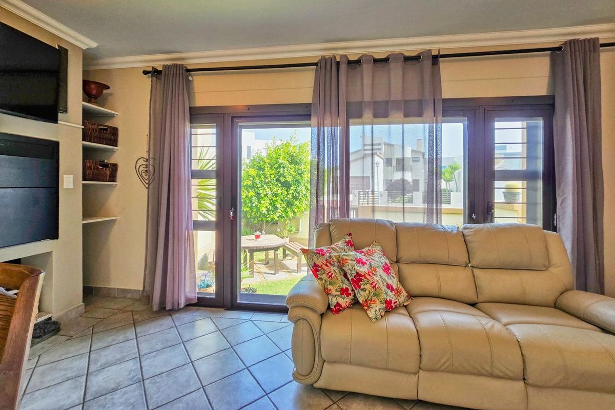 A bright living room featuring tiled flooring, built-in shelving, and large sliding glass doors that provide direct access to the rear garden area.