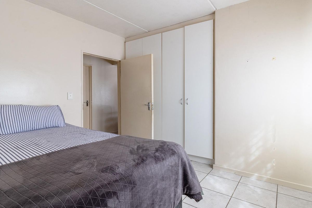 A bedroom featuring tiled flooring and built-in cupboards, offering a functional space with neutral finishes ready for personalization.