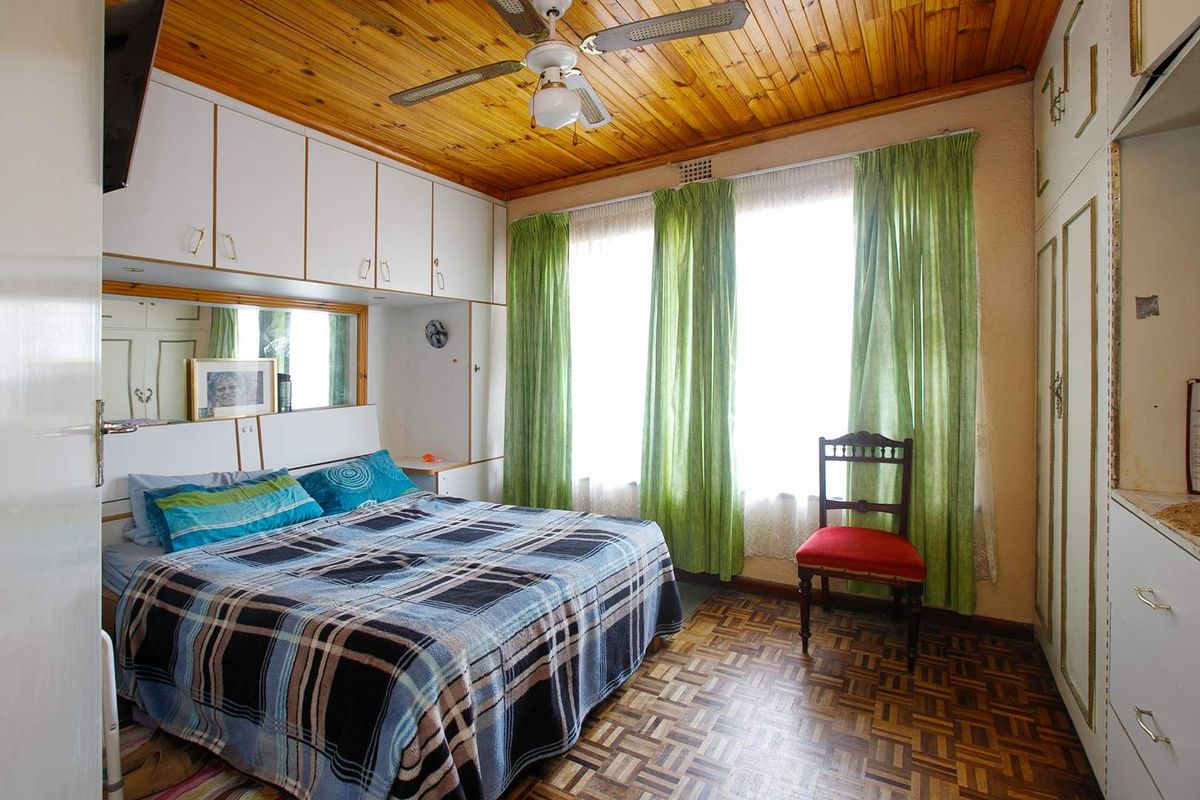 A bedroom featuring parquet flooring, a timber-paneled ceiling, ceiling fan, and extensive built-in cabinetry surrounding the bed area.