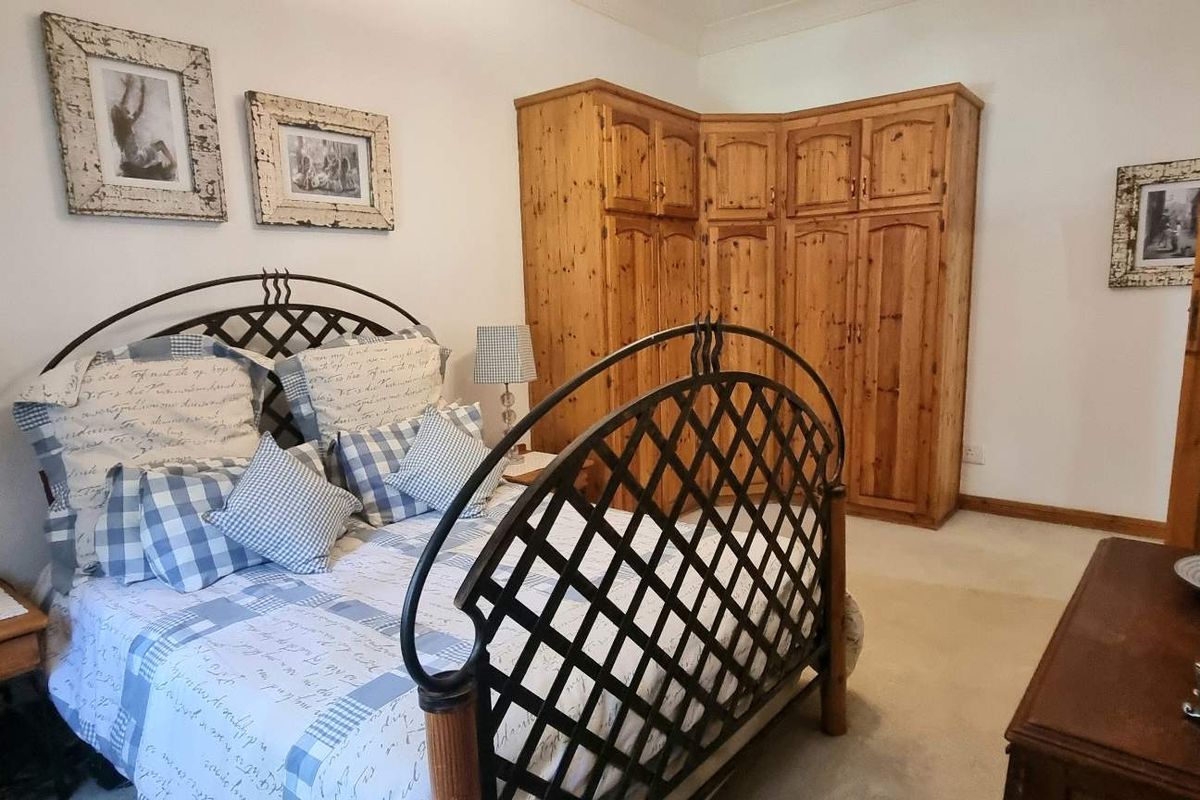 A bedroom featuring built-in wooden cabinetry and carpeted flooring, offering a functional layout with traditional design elements.