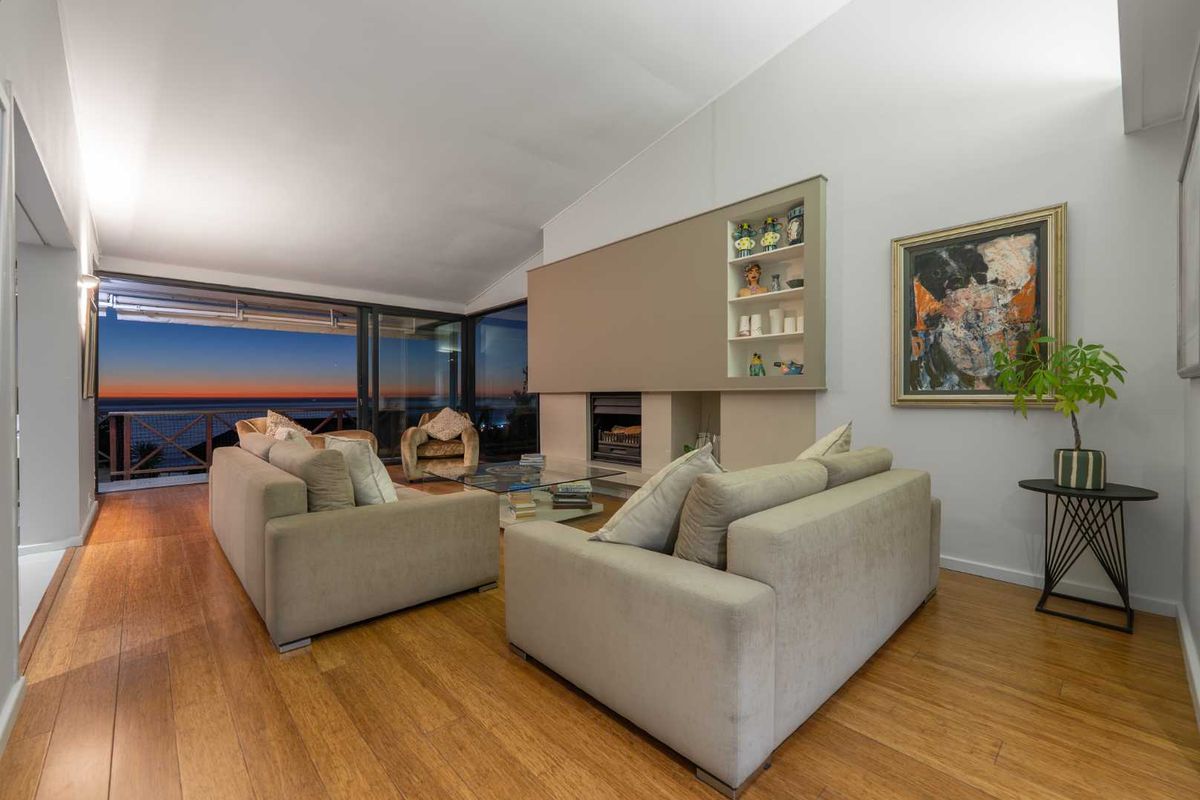 Spacious living room featuring hardwood flooring, a built-in fireplace with shelving, and large sliding glass doors opening to a scenic ocean view.