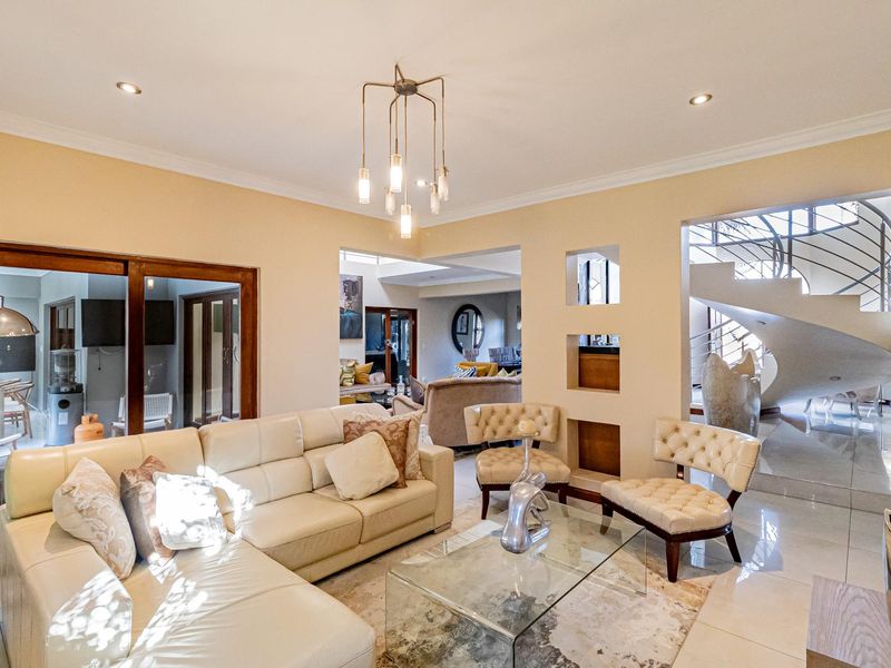 Spacious living area featuring tiled floors, recessed lighting, decorative wall niches, and a striking spiral staircase leading to the upper level.